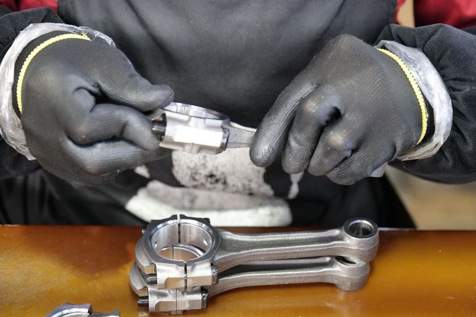 Gloved hands holding a machined metal part